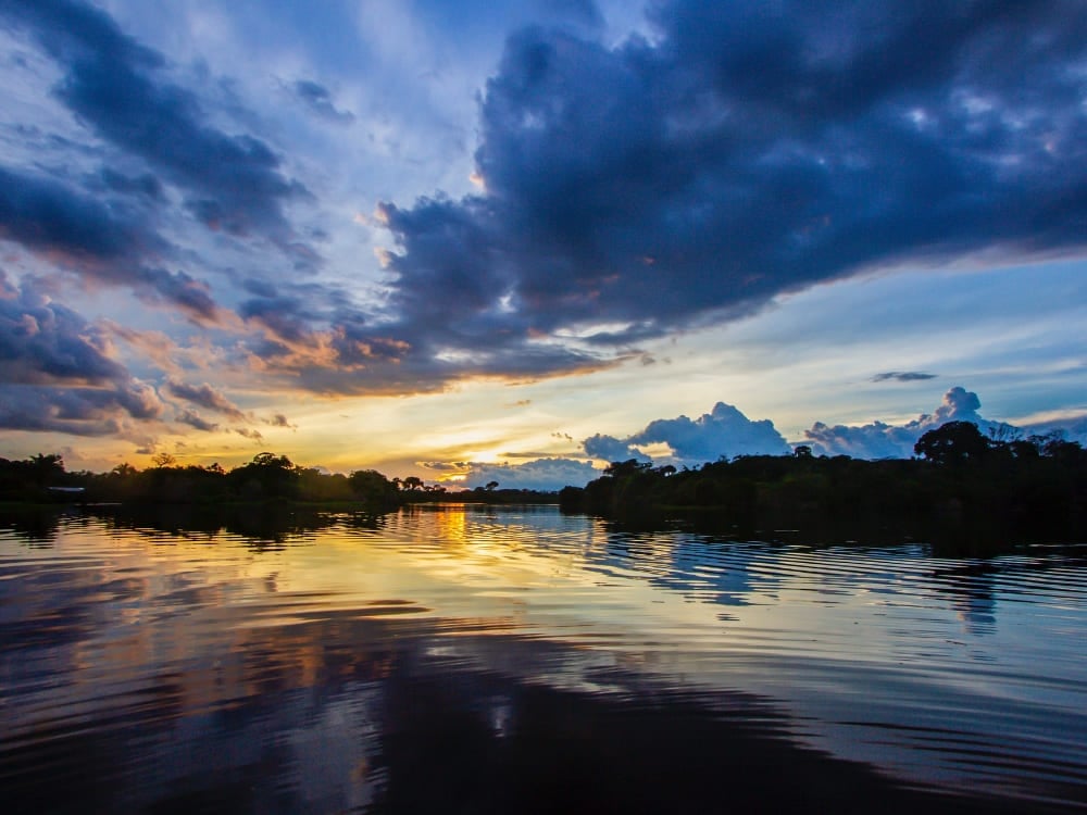 Un atardecer de colores reflejándose en las aguas tranquilas del río Amazonas bordeado por la selva. Un atardecer de colores reflejándose en las aguas tranquilas del río Amazonas bordeado por la selva.