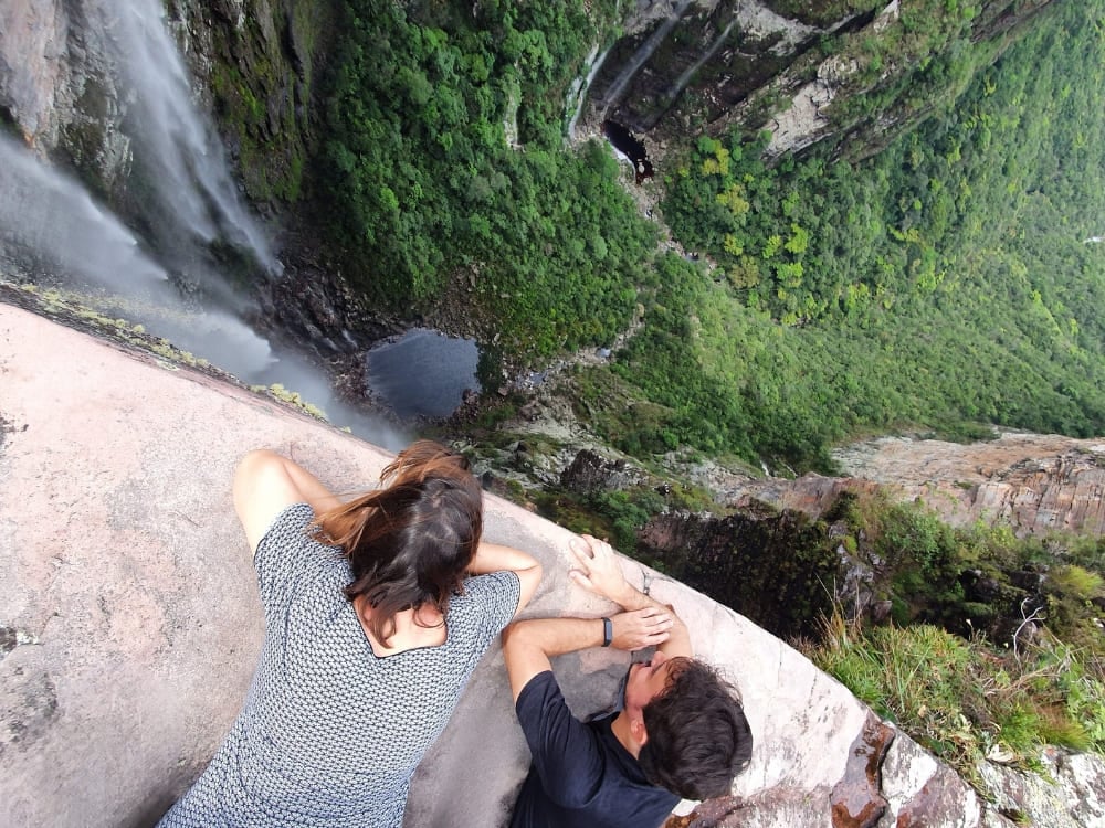 Due escursionisti guardano dall'alto della parete il Cachoeirão che precipita nel canyon verde della Vale do Pati. Due escursionisti guardano dall'alto della parete il Cachoeirão che precipita nel canyon verde della Vale do Pati.