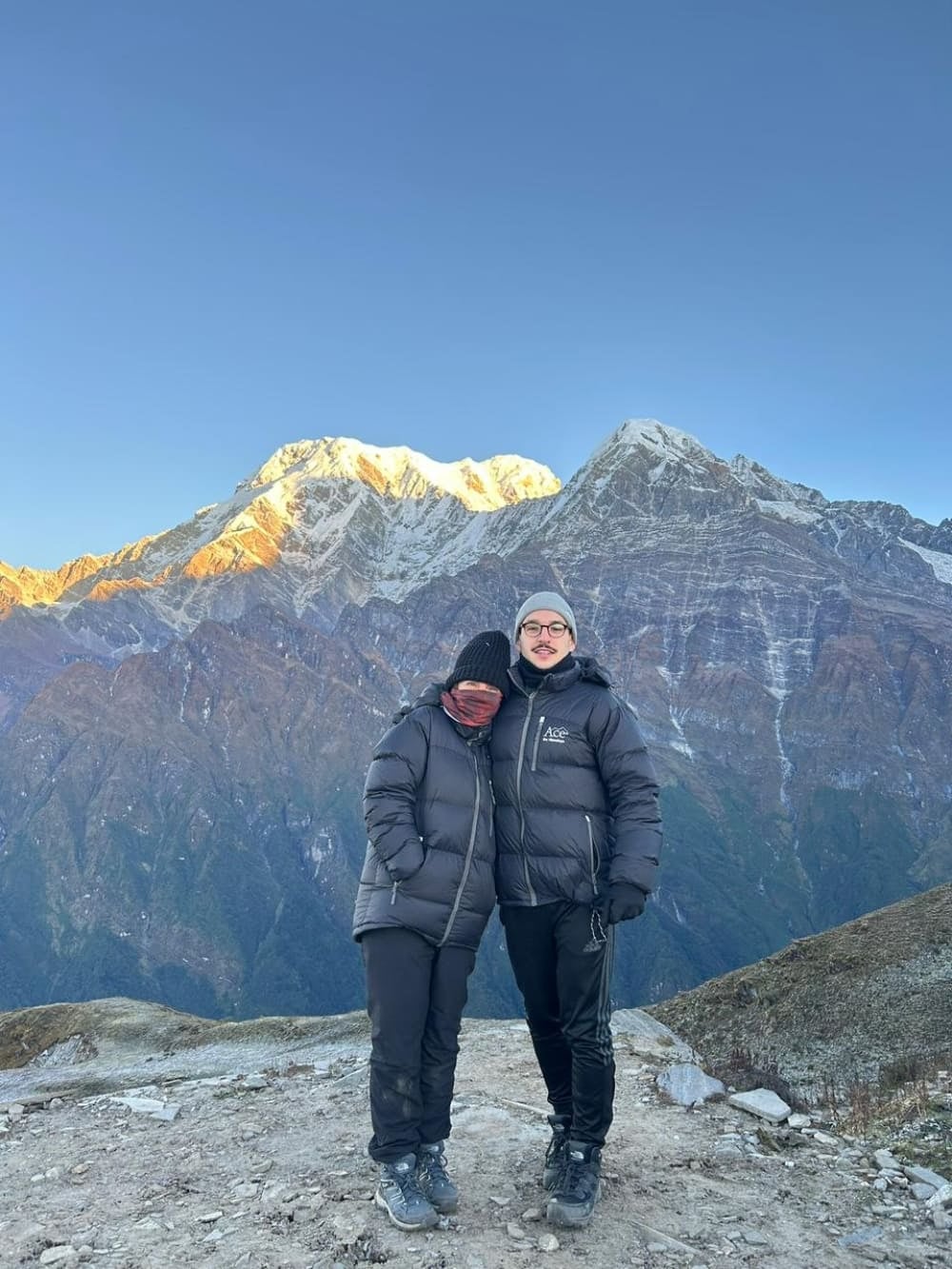 Mutter und Sohn Mila und Lorenzo tragen schwere Winterkleidung und umarmen sich vor den schneebedeckten Gipfeln im Himalaya nach einem frühmorgendlichen Aufstieg. Mutter und Sohn Mila und Lorenzo tragen schwere Winterkleidung und umarmen sich vor den schneebedeckten Gipfeln im Himalaya nach einem frühmorgendlichen Aufstieg.