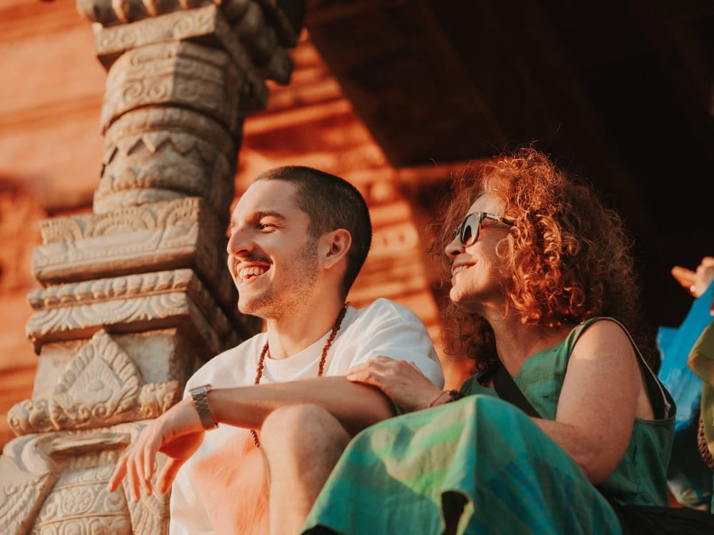 Mila Ricetti und ihr Sohn Lorenzo sitzen lächelnd zusammen an einem historischen Backsteintempel während ihrer Ökotourismus-Expedition in Nepal. Mila Ricetti und ihr Sohn Lorenzo sitzen lächelnd zusammen an einem historischen Backsteintempel während ihrer Ökotourismus-Expedition in Nepal.