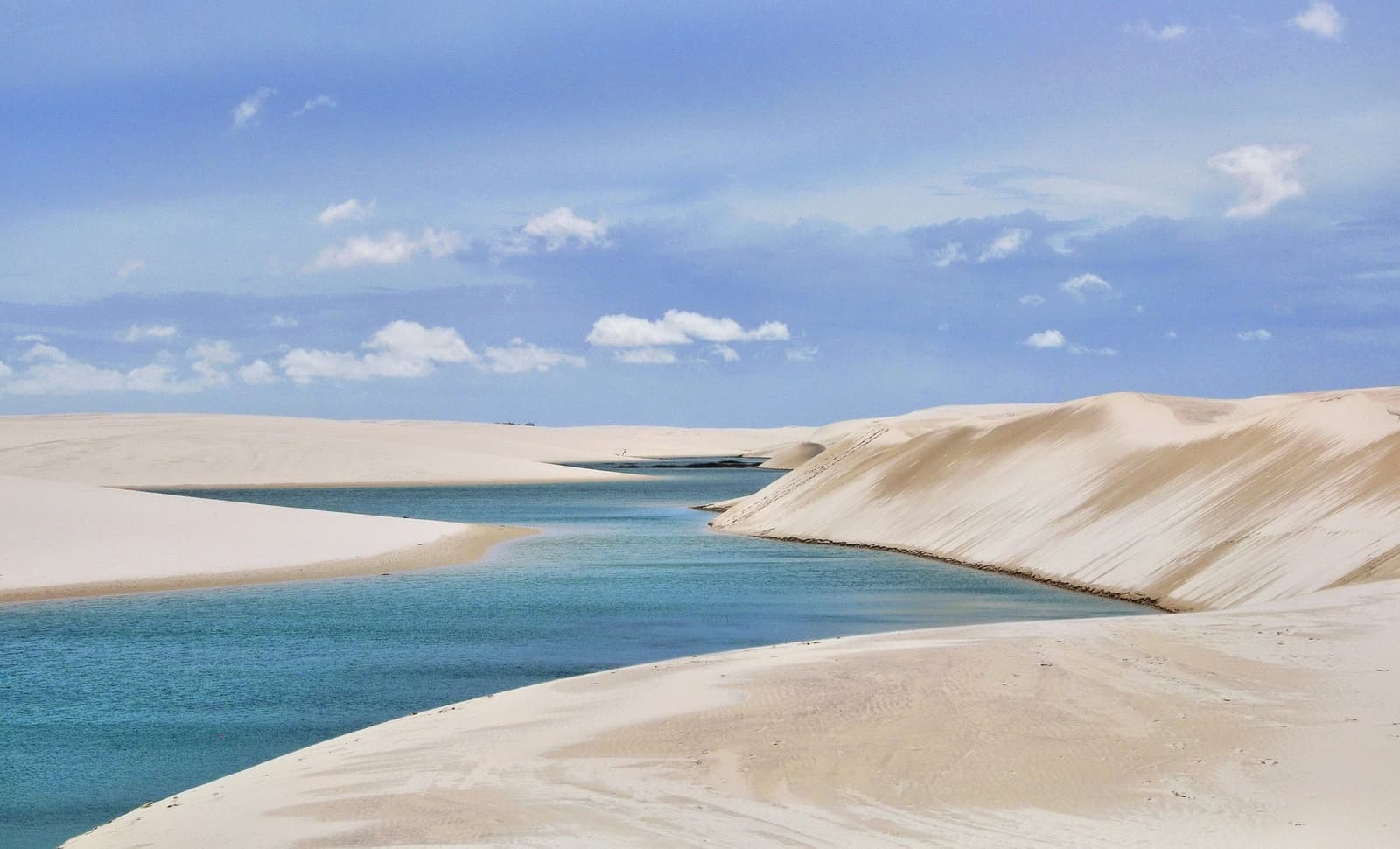 Süßwasser, weißer Sand und ein Himmel, der jeden Tag anders aussieht. Türkisfarbene Regenwasserlagune zwischen weitläufigen weißen Sanddünen unter blauem Himmel im Nationalpark Lençóis Maranhenses