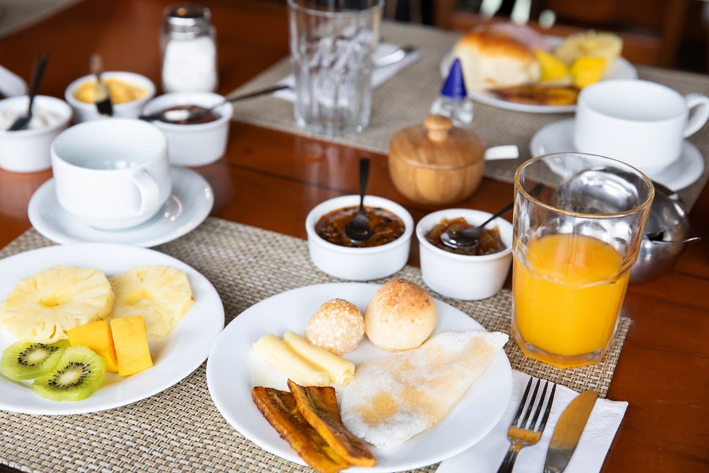 Ein gutes Frühstück, bevor der Amazonas den Tag übernimmt. Ein reichhaltiges Frühstück an Bord einer Amazonas-Flusskreuzfahrt in Brasilien mit Pão de Queijo, Tapioca, gebratenen Kochbananen, Käse, frischer Ananas, Kiwi, Orangensaft, Fruchtaufstrichen und Kaffeetassen auf einem geflochtenen Tischset