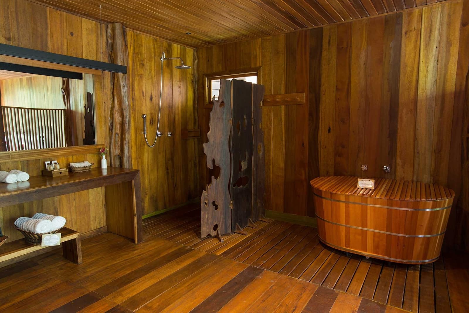 Ein heißes Bad mitten im Regenwald, der Urwald wartet direkt vor dem Fenster. Rustikales Holzbadezimmer im Mirante do Gavião mit einem Fass-Badebottich, Regendusche und einer natürlichen Holztrennwand sowie gefalteten weißen Handtüchern