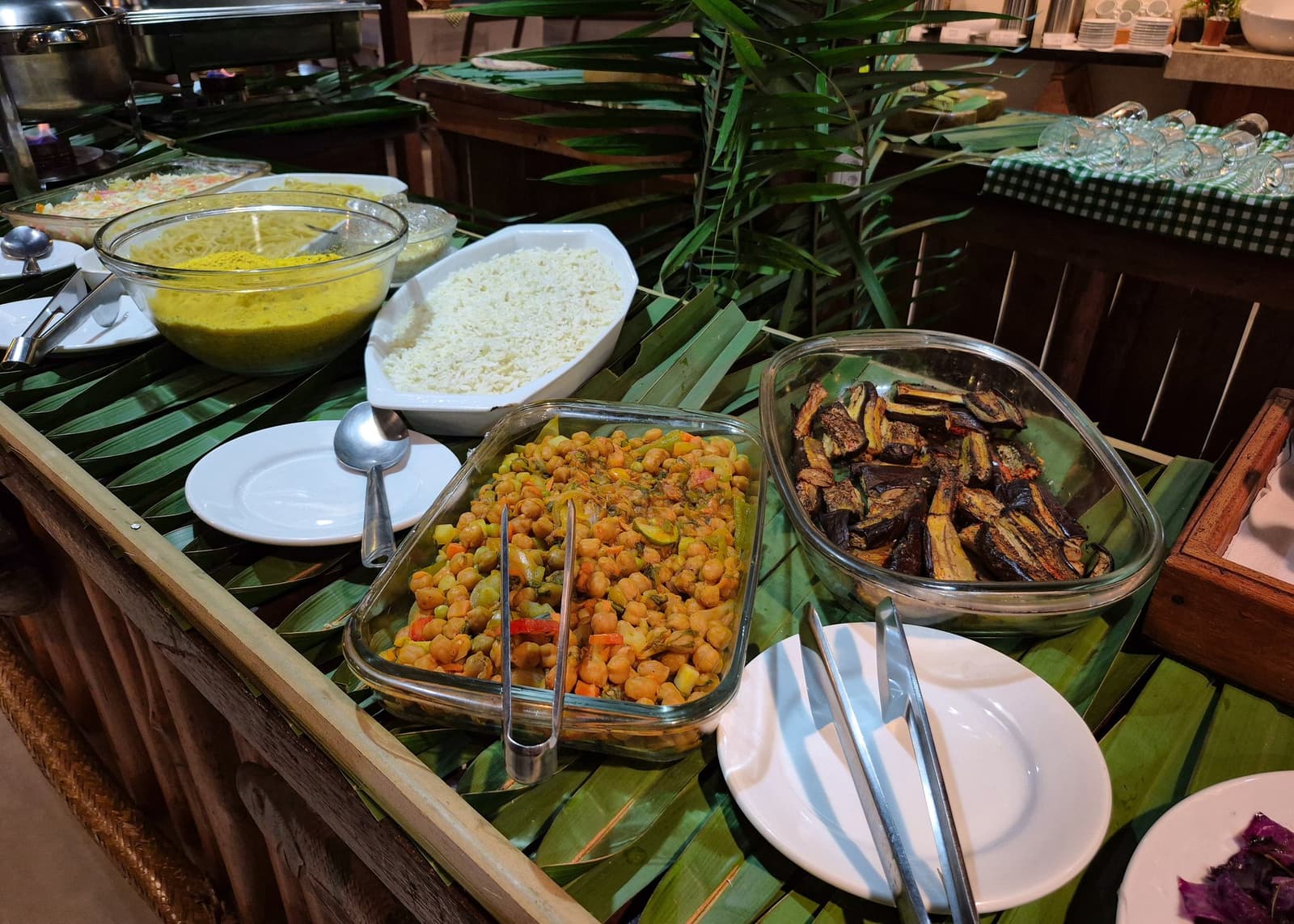 Nach einem Tag auf dem Fluss schmeckt alles doppelt so gut. Ein farbenfrohes vegetarisches Buffet im Amazon Turtle Lodge mit würzigen Kichererbsen, gerösteten Auberginenscheiben, weißem Reis und einer gelben Sauce, serviert in Glasschalen auf frischen Bananenblättern