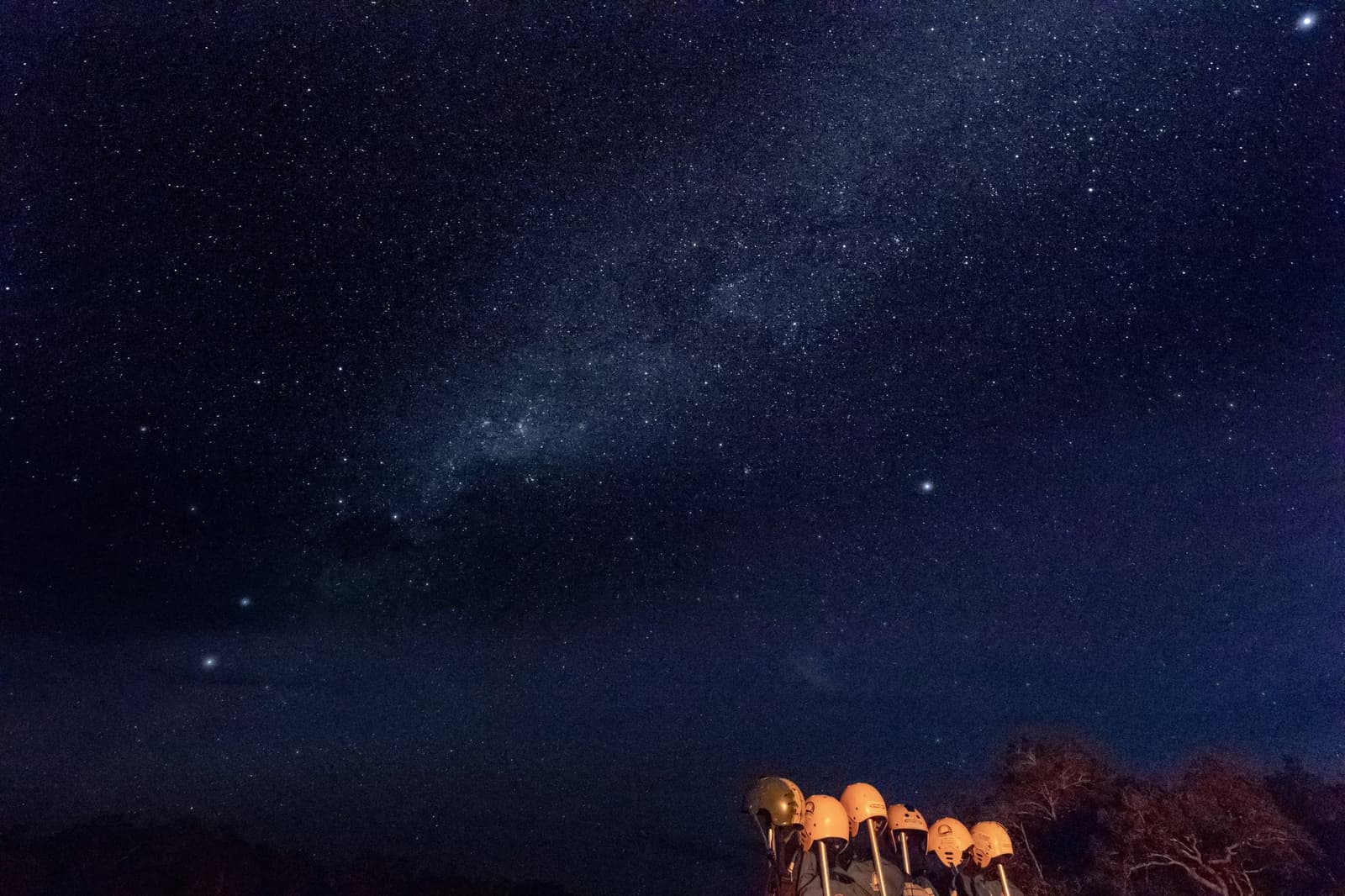 Teleskope aufgebaut, kein Stadtlicht weit und breit, der Cerrado gehört der Nacht. Photo: Alberto Andrich Eine Reihe amber leuchtender Teleskope im Vordergrund unter einem mit der Milchstraße übersäten Nachthimmel auf einer Jalapão-Trekkingtour