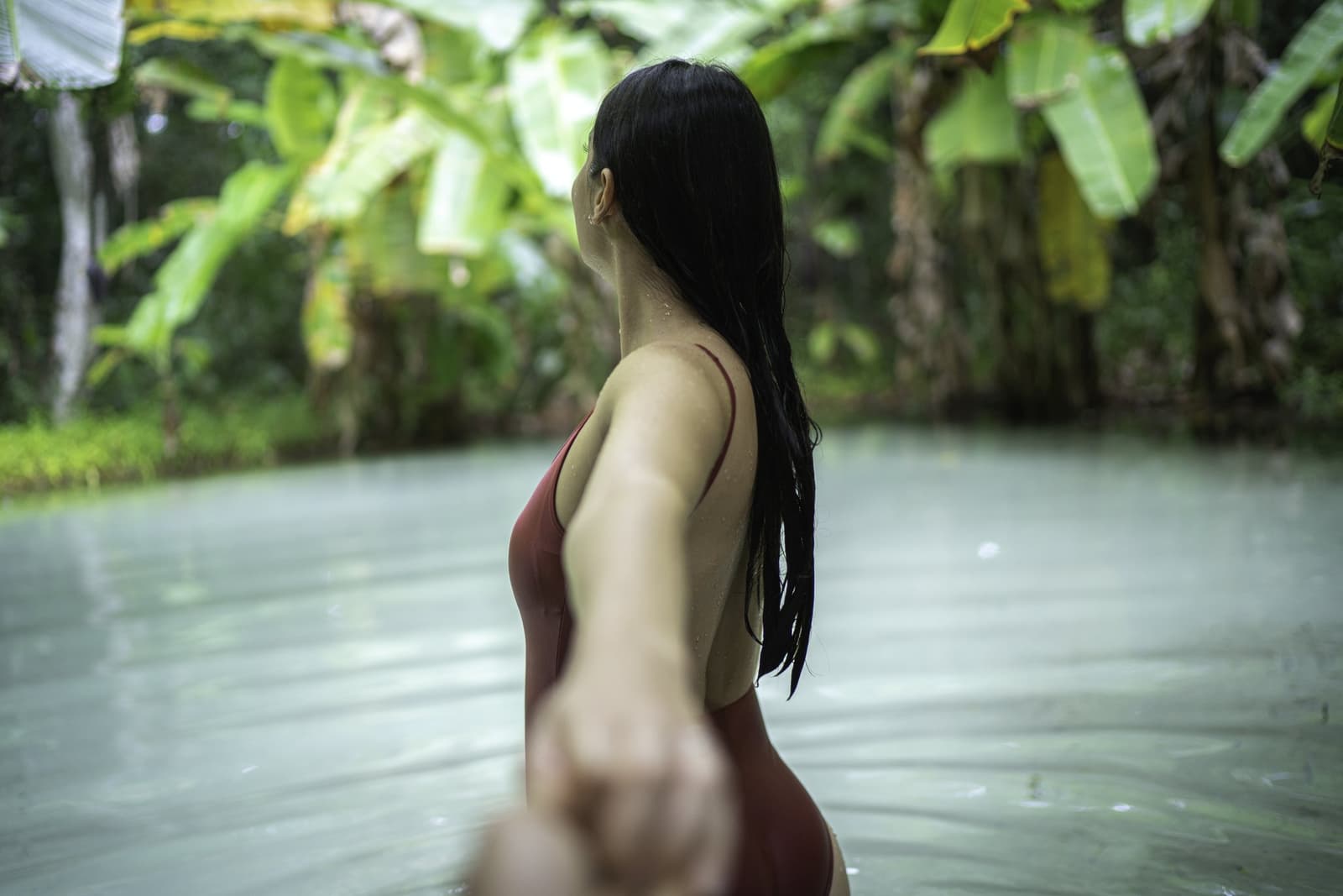 Kühles Quellwasser, stille Natur — ein unvergesslicher Moment. Photo: FG Trade Eine Frau in rotem Badeanzug watet durch das ruhige, milchig-grüne Wasser eines Fervedouro auf einer 4-tägigen Jalapão-Tour, umgeben von üppiger tropischer Vegetation