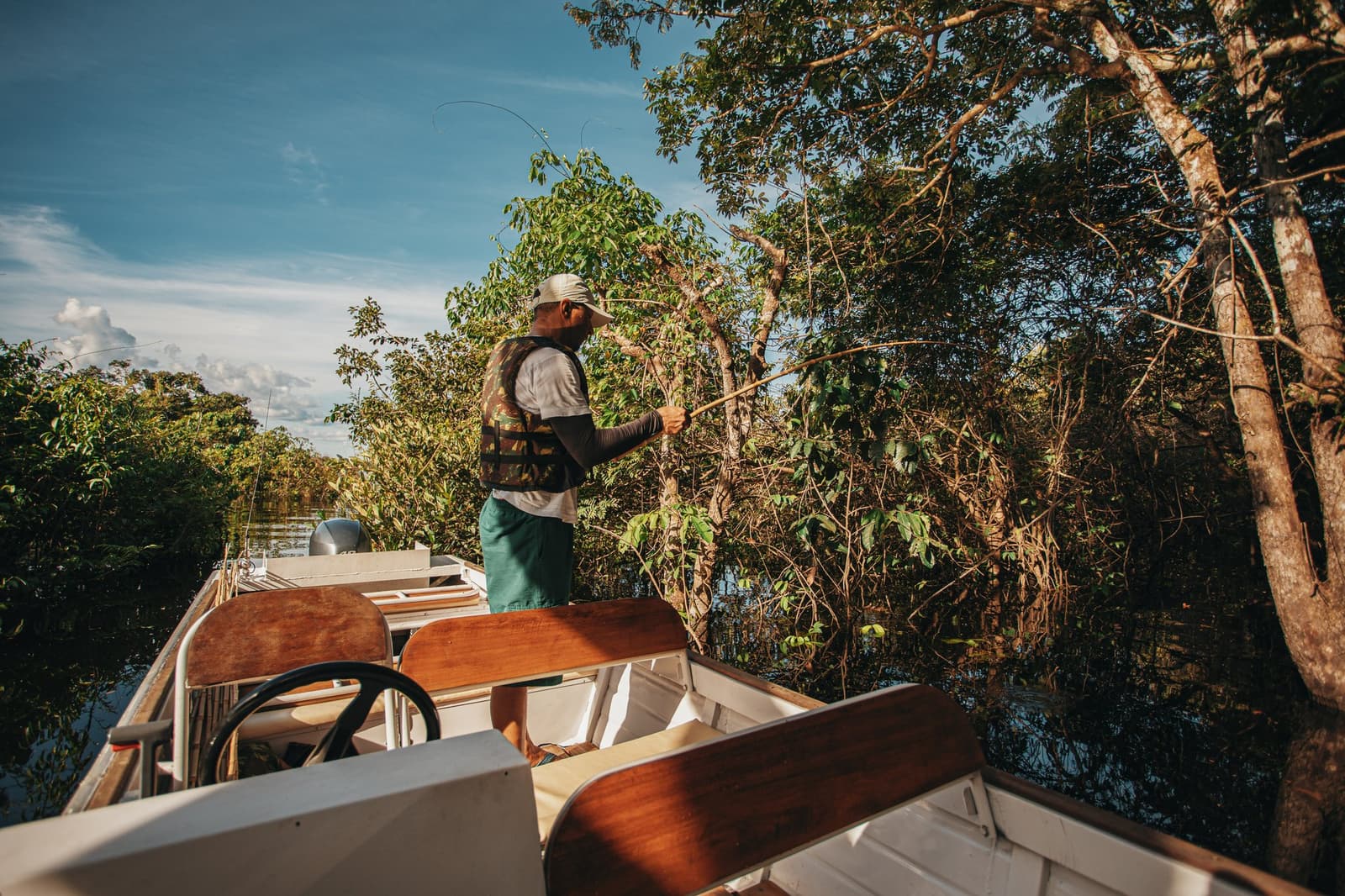 Ein Bambusstab, ruhige Hand, schwarzes Wasser, der Amazonas setzt die Regeln. Ein Guide steht am Bug eines kleinen Motorboots mit einer Angelrute in der Hand und wirft die Leine in Richtung des dichten Ufervegetation beim Anavilhanas Jungle Lodge Brazil