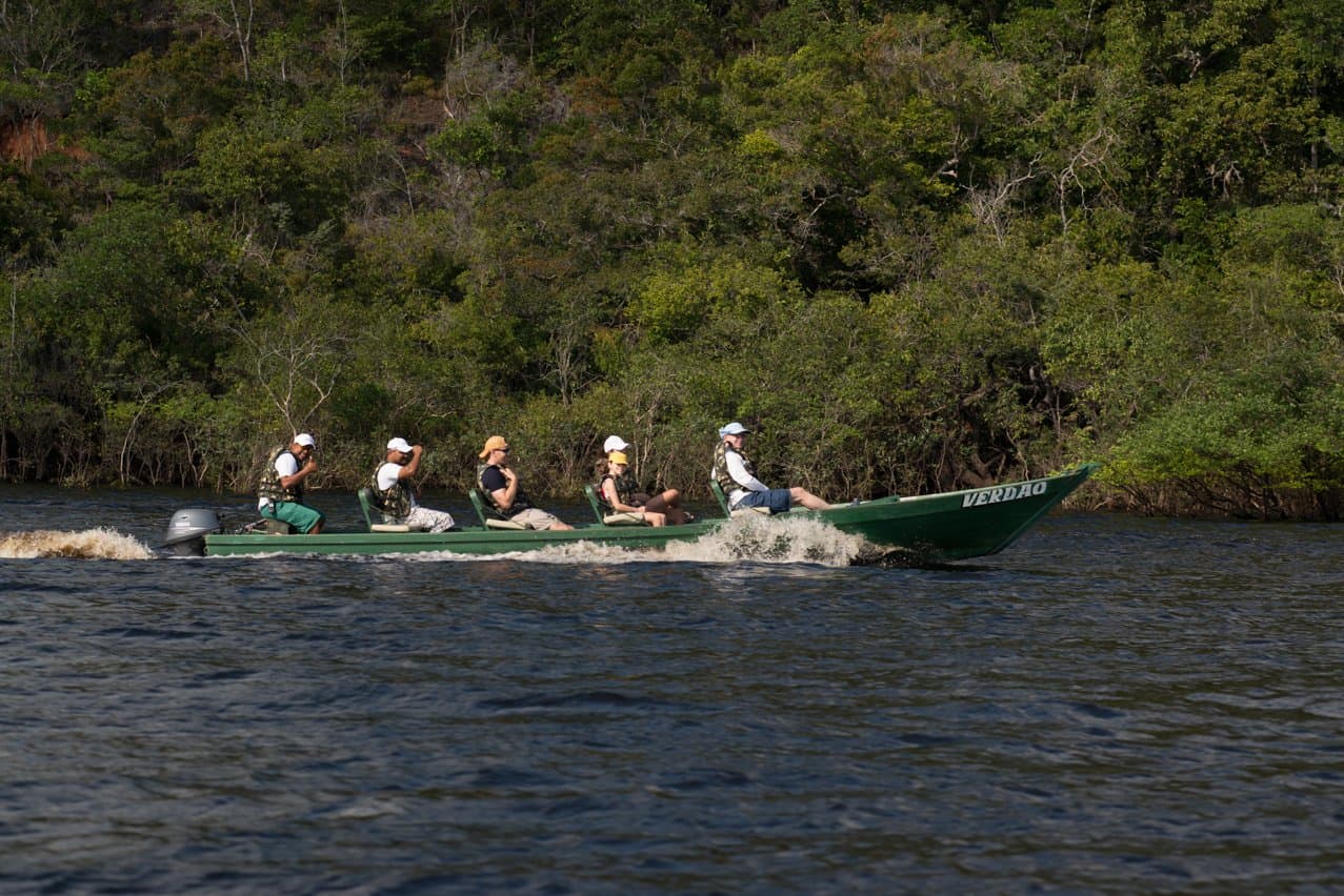 Auf dem Fluss merkt man schnell, wie groß der Amazonas wirklich ist. Eine Gruppe Ökotouristen in Schwimmwesten rast an Bord eines grünen Motorboots über den Rio Negro auf einer Expedition der Anavilhanas Jungle Lodge Brazil, während dichter Galeriewald das gegenüberliegende Ufer säumt