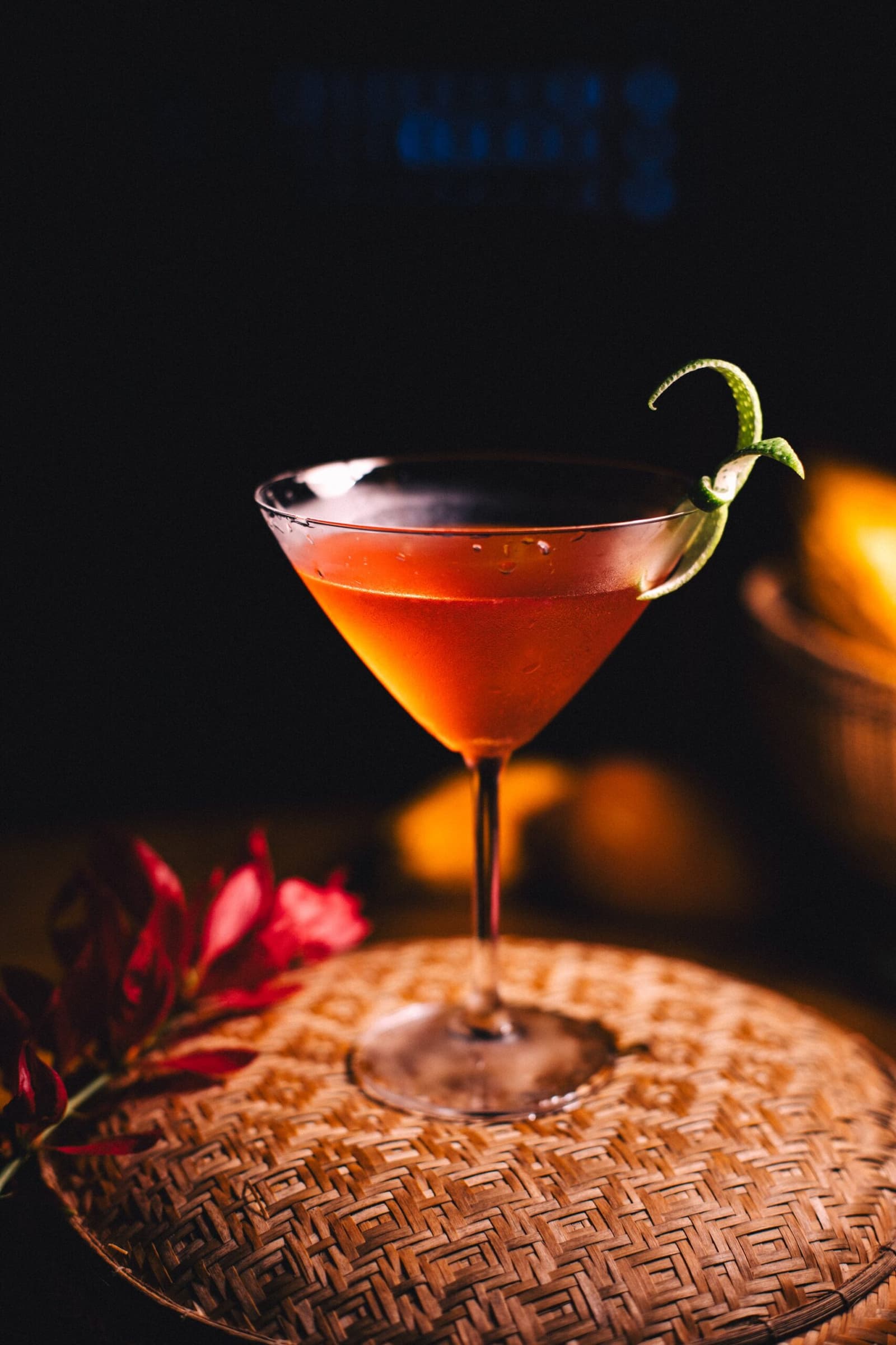Nach einem Tag im Regenwald schmeckt jeder Schluck anders. Ein tiefrotes Cocktail im Martiniglas mit Limettenzeste, serviert auf einem geflochtenen Tablett neben einer roten Tropenblüte in der Anavilhanas Jungle Lodge Brazil