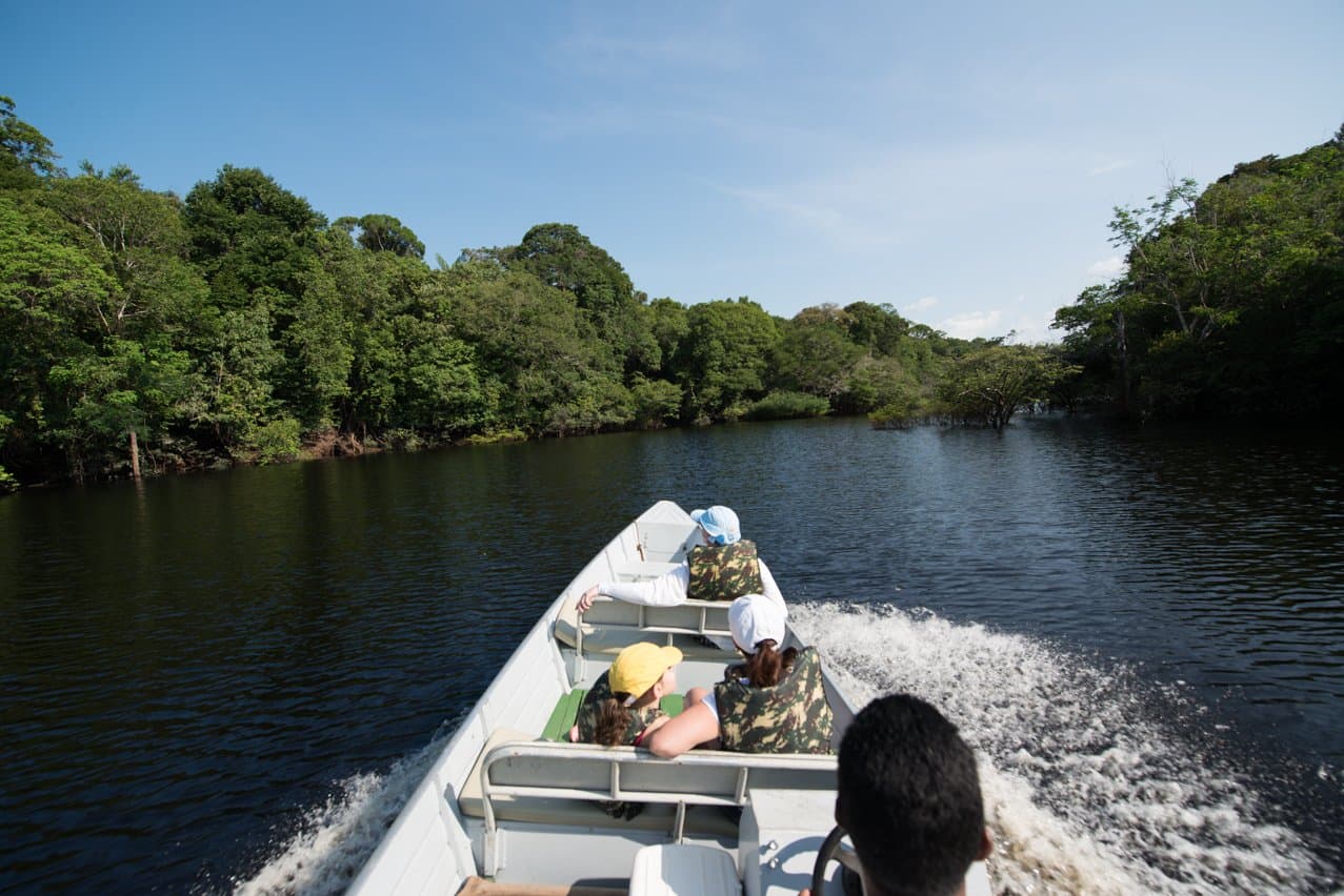 Schwarzes Wasser, grüne Wände, kein Zeitplan. Gäste in Schwimmwesten rasen in einem Motorboot über einen schwarzwassrigen Amazonasfluss bei der Anavilhanas Jungle Lodge Brazil, begleitet von dichtem Regenwalddach auf beiden Seiten