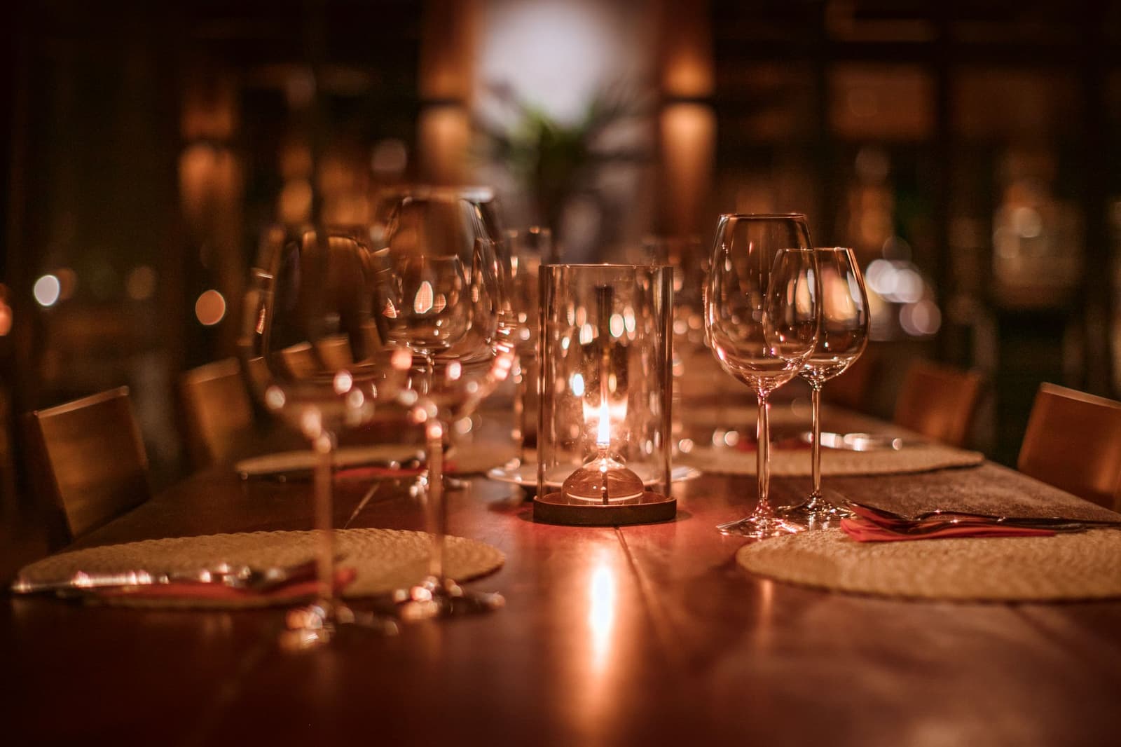 Ein Abendessen, bei dem der Dschungel direkt vor der Tür wartet. Ein langer polierter Holztisch im Cristalino Jungle Lodge, gedeckt mit Kristallweingläsern, geflochtenen Untersetzern, roten Servietten und einer leuchtenden Glaskerzenlaterne, die warmes Bernsteinlicht verbreitet