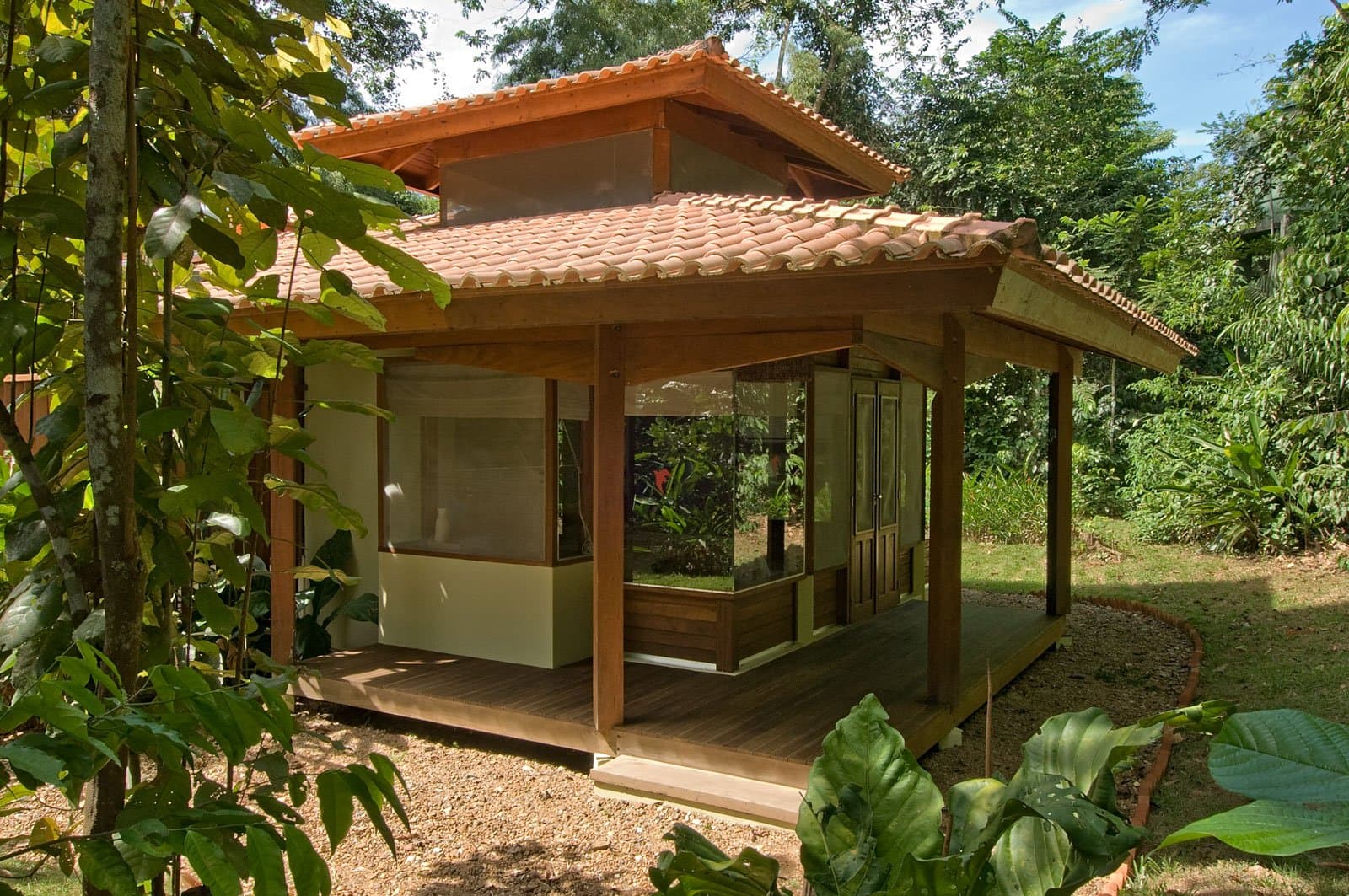 Mitten im Wald schlafen, ohne auf Komfort zu verzichten. Ein Holzbungalow mit Terrakottadach und umlaufender Holzterrasse im Cristalino Jungle Lodge, eingebettet in üppige tropische Gartenvegetation