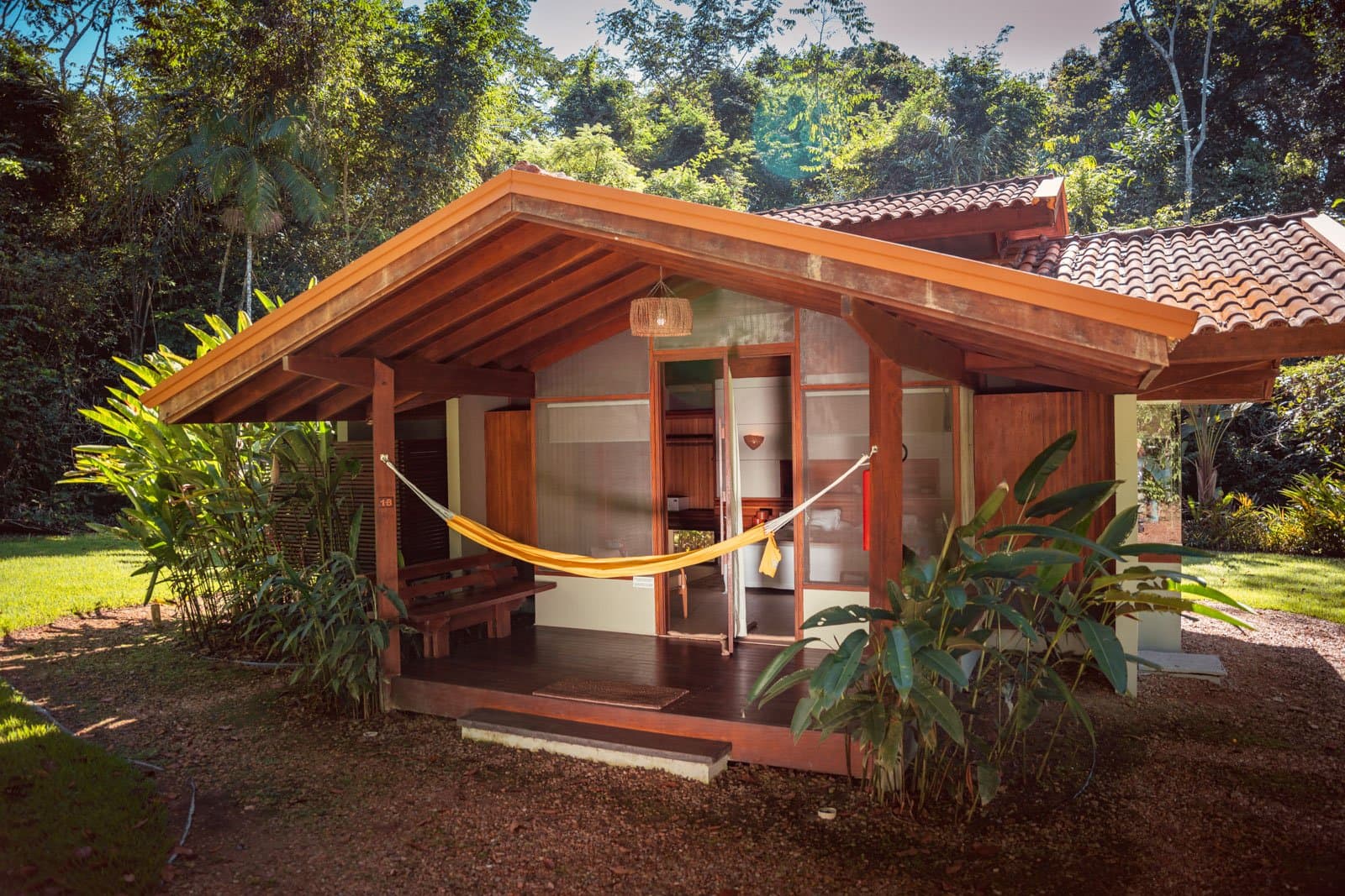 Hängematte, Waldrauschen, kein Terminkalender in Sicht. Ein Holzbungalow im Cristalino Jungle Lodge mit einer gelben Hängematte auf der überdachten Veranda, umgeben von üppiger tropischer Vegetation