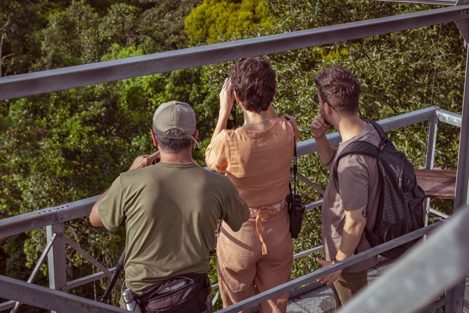 Fernglas raus, Augen auf, der Regenwald behält seine Geheimnisse nicht lange für sich. Drei Besucher beobachten das Regenwalddach mit Ferngläsern von einem Stahlturm im Cristalino Jungle Lodge