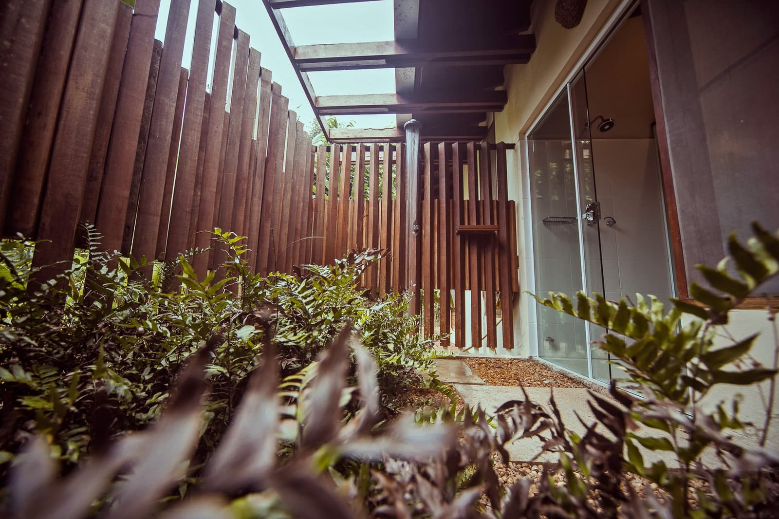 Duschen mit Dschungel-Feeling, die Natur kommt fast mit rein. Eine private Außendusche im Cristalino Jungle Lodge, umgeben von vertikalen Hartholzlamellen und üppigem tropischen Grün unter freiem Himmel