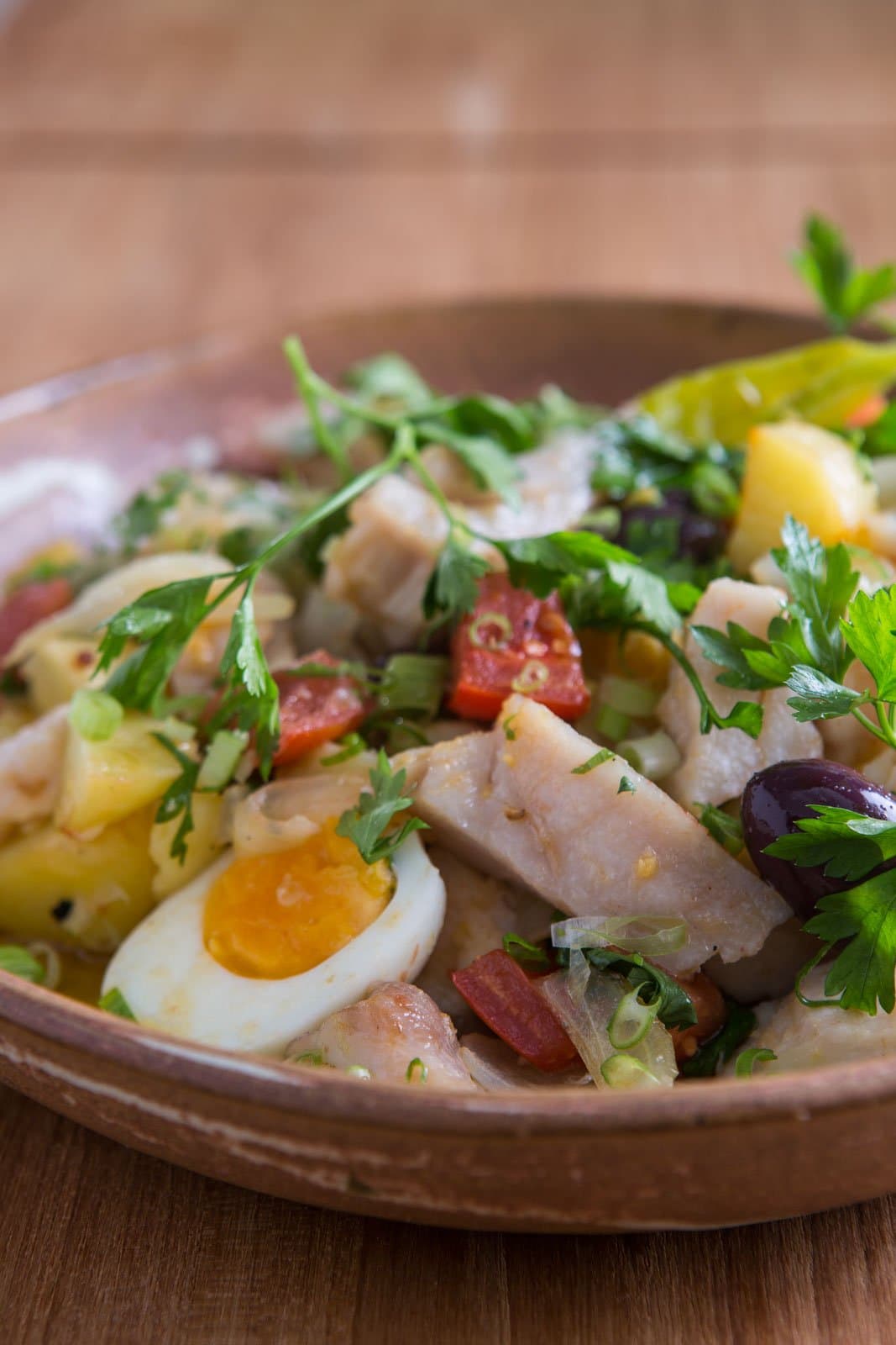 Portugiesische Seele, serviert mitten im Regenwald. Eine rustikale Tonschüssel mit zerzupftem weißem Fisch, hartgekochten Eiern, gelben Kartoffeln, schwarzen Oliven, roter Wurst, Frühlingszwiebeln und frischer Petersilie im Cristalino Jungle Lodge