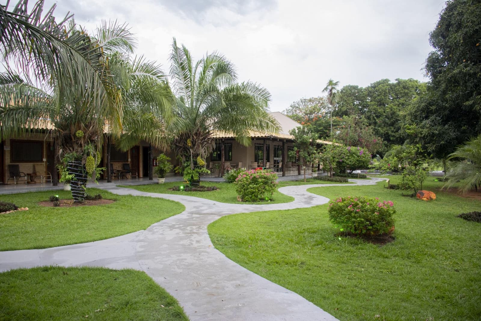 Schon der erste Schritt auf dem Gelände schaltet den Alltag ab. Ein geschwungener Betonweg führt durch einen üppigen tropischen Garten zu flachgedeckten Lodge-Bungalows, umgeben von Palmen und blühenden Sträuchern