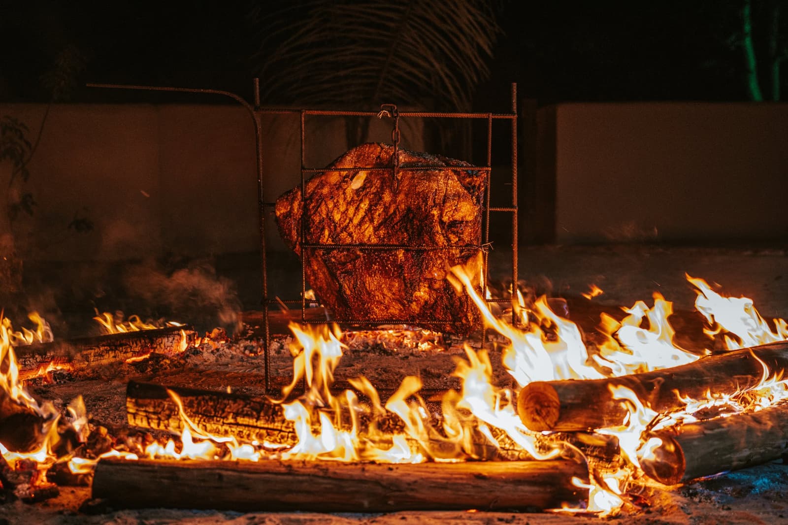 Le genre de rôti qui demande du bois, du feu et beaucoup de patience. Une pièce de viande entière rôtissant lentement dans une cage en fer forgé au-dessus des flammes d'un feu de bois en pleine nuit à la Pousada Trijunção, au cœur du Cerrado brésilien