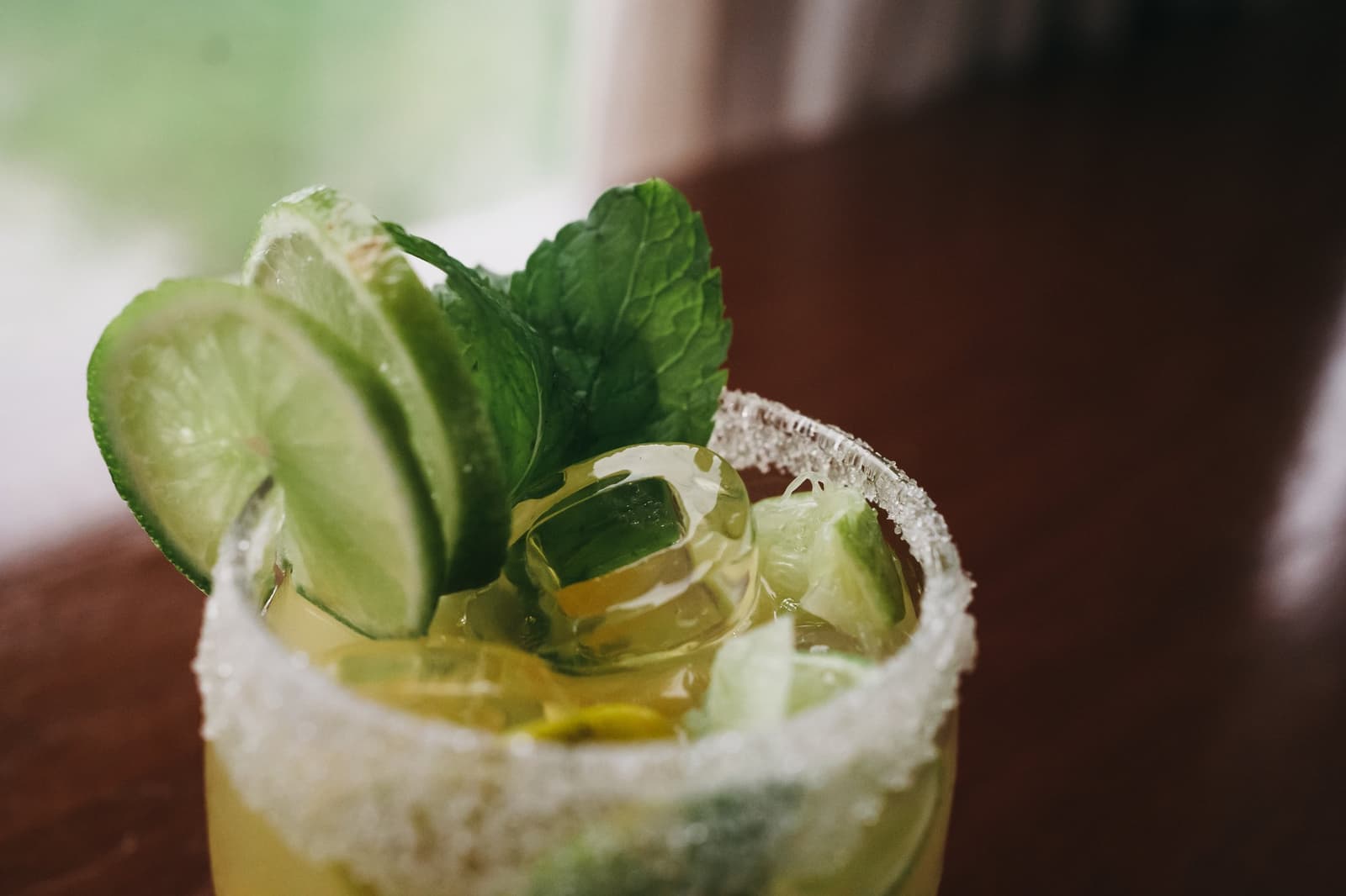 Limette, Gurke, Zuckerrand, Flussreisen können sich sehen lassen. Nahaufnahme eines Cocktails auf einer Luxus-Amazonaskreuzfahrt in Brasilien, garniert mit frischen Limettenscheiben, Gurkenscheiben und einem Minzzweig in einem zuckergeränderten Glas