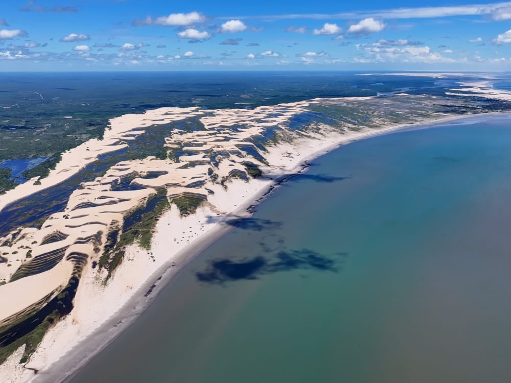 . Aerial perspective of the Delta do Parnaiba showing the river branching into the ocean alongside large coastal sand dunes.
