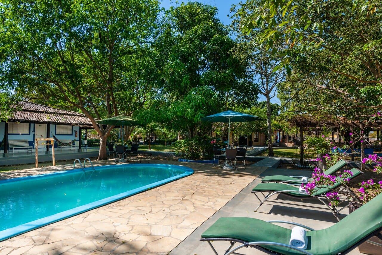 Steinpflaster, Blätterschatten und blühende Bougainvilleen — Erholung pur nach einem Tag im Feuchtgebiet. Überdachter Außenpool mit Sonnenliegen und Bougainvillea in einer Lodge für die Pantanal-Tour ab Cuiabá in Poconé