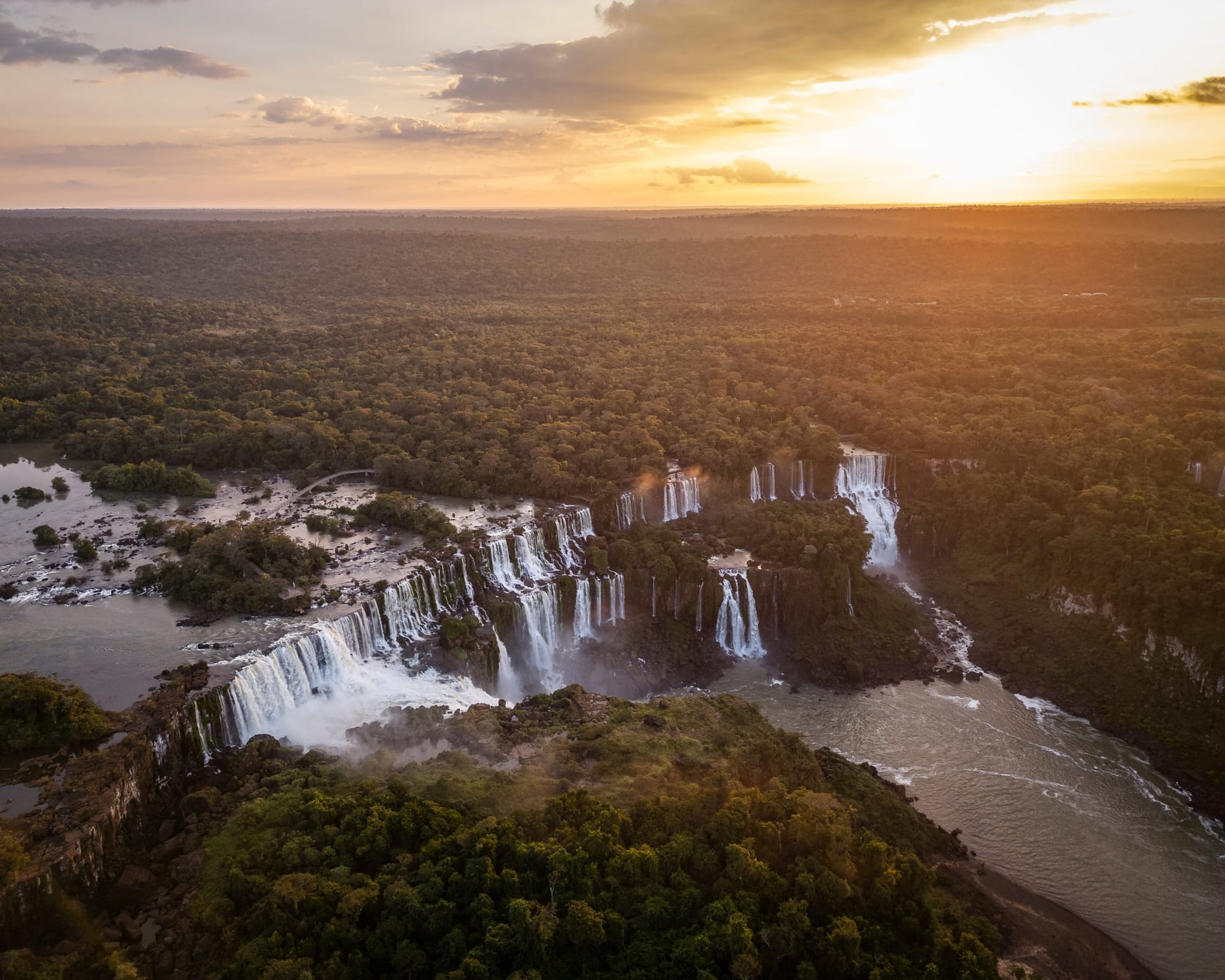 Vista aérea de las Cataratas del Iguazú al atardecer, con decenas de saltos entre el Bosque Atlántico, Brasil. Vista aérea de las Cataratas del Iguazú al atardecer, con decenas de saltos entre el Bosque Atlántico, Brasil.