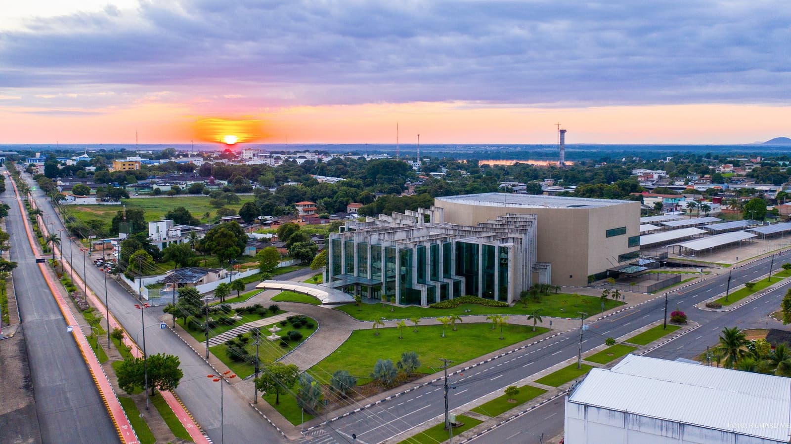 Boa Vista in het avondlicht, de stad die je uitzendt richting de oudste rotsen van de aarde. Luchtfoto van Boa Vista bij zonsondergang, met een modern glazen overheidsgebouw, brede lanen en de stad die zich uitstrekt onder een roze-oranje lucht.