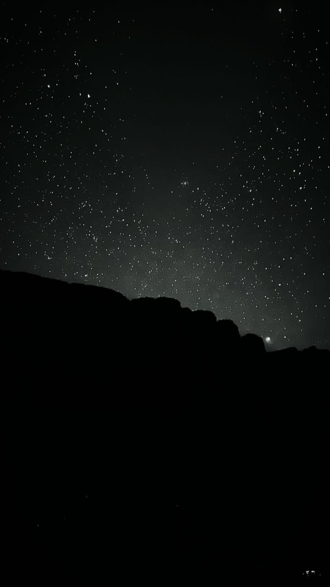 Eén planeet, duizend sterren, en eindelijk stilte. Dicht sterrenveld boven de donkere silhouet van een rotsachtige bergkam tijdens een Mount Roraima-expeditie, met één heldere planeet laag aan de horizon