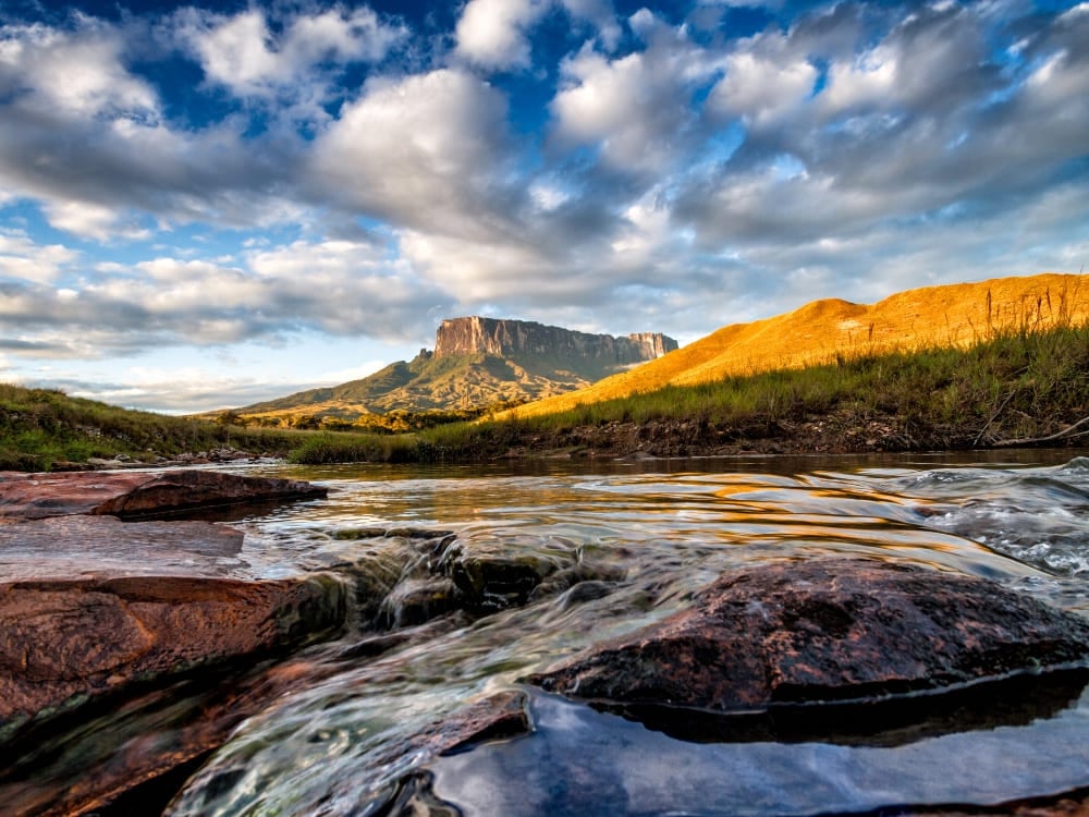 Il tepui Kukenán accanto al Monte Roraima riflesso in un fiume nell'ora dorata Il tepui Kukenán accanto al Monte Roraima riflesso in un fiume nell'ora dorata