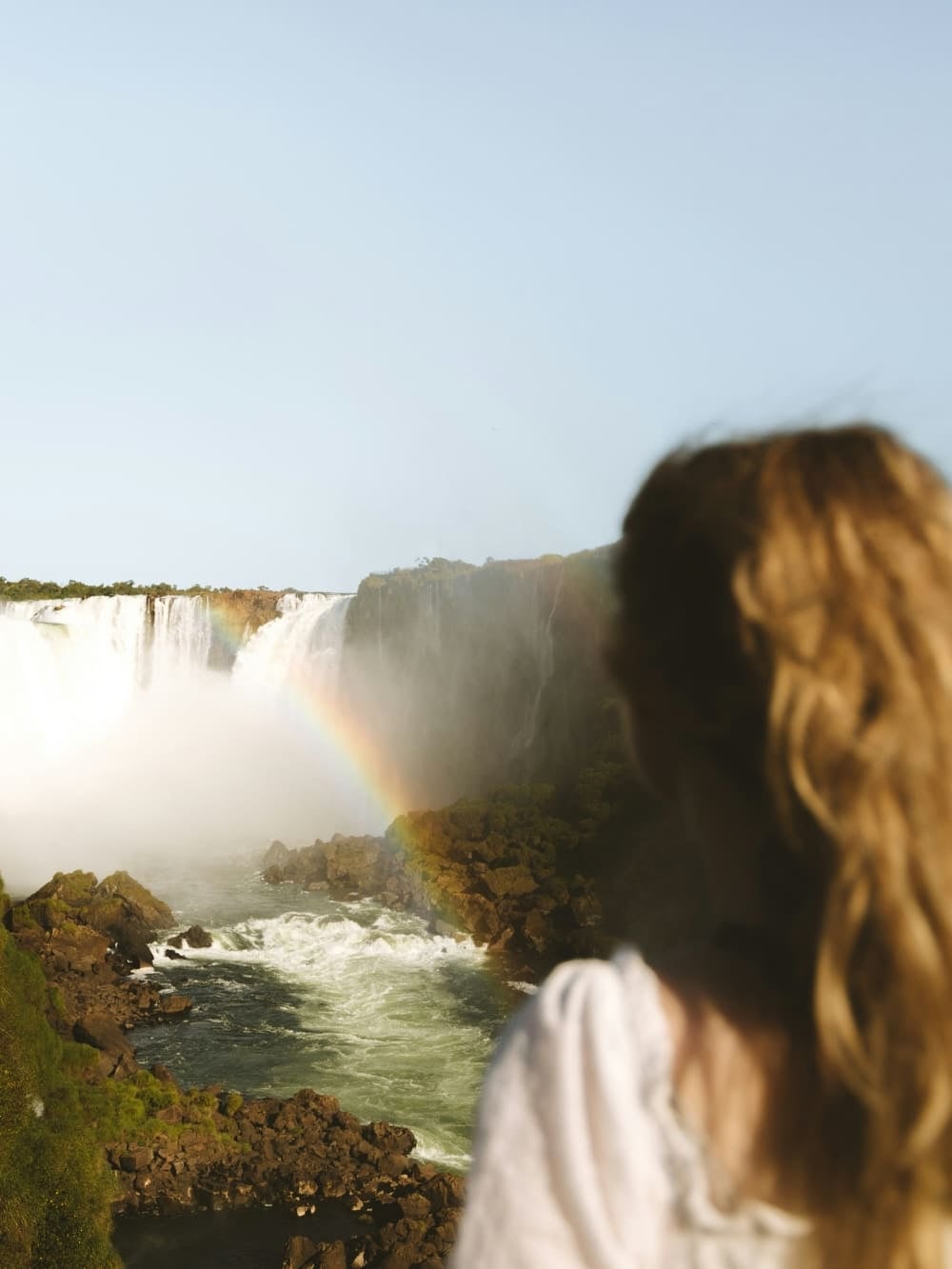 Una mujer contempla las Cataratas del Iguazú con un arcoíris formándose en la bruma, Brasil. Una mujer contempla las Cataratas del Iguazú con un arcoíris formándose en la bruma, Brasil.