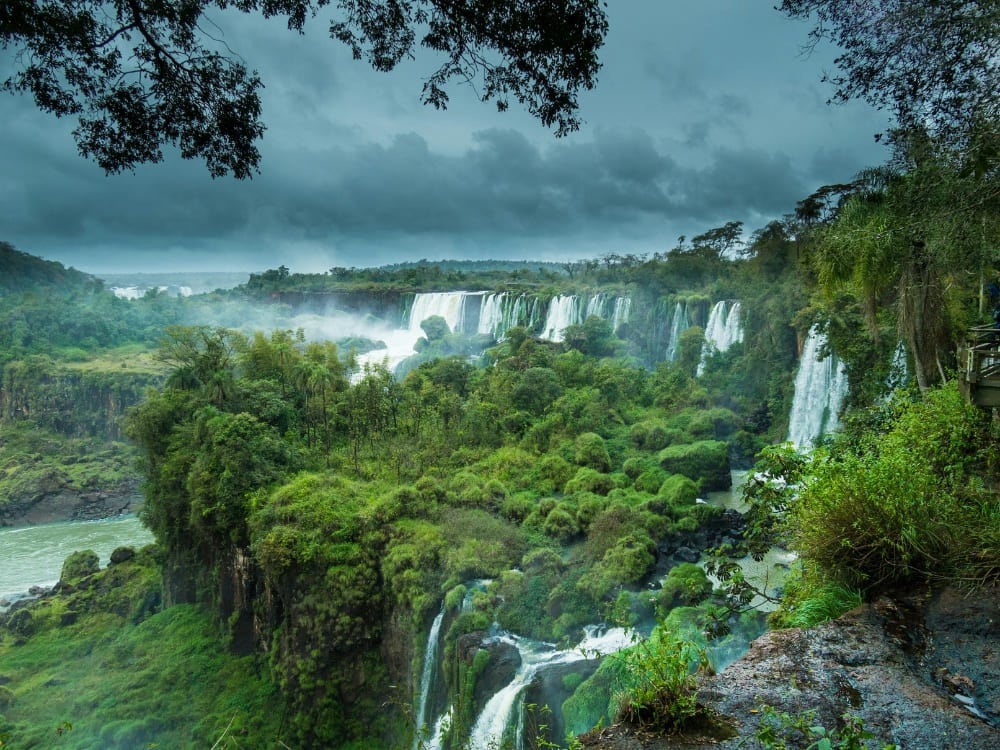 Cataratas del Iguazú vistas desde un mirador en la selva, bajo las nubes de tormenta de la temporada de lluvias, Brasil. Cataratas del Iguazú vistas desde un mirador en la selva, bajo las nubes de tormenta de la temporada de lluvias, Brasil.